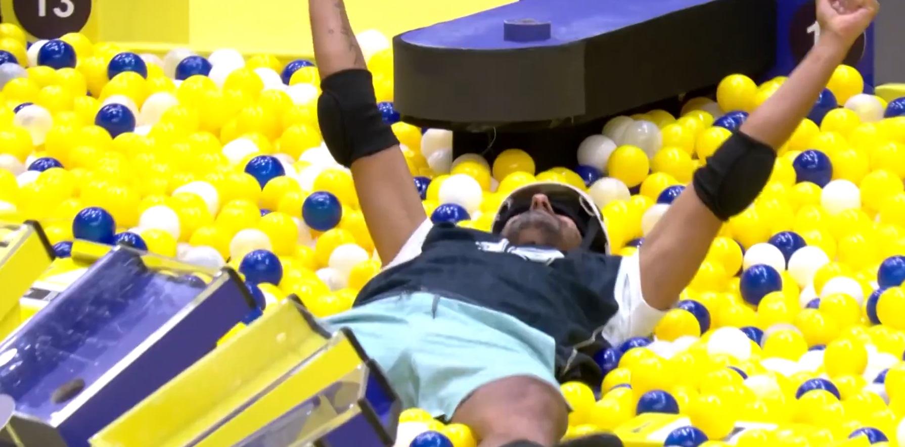 Alberto Cowboy em uma piscina de bolinhas, com os braços erguidos, possivelmente celebrando ou descansando em meio às esferas coloridas, na Prova do Líder do BBB 26.