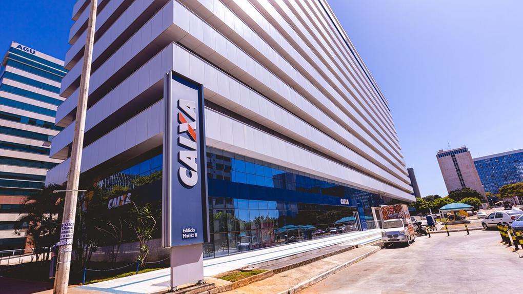 Edifício moderno da CAIXA Econômica Federal na cidade, destacando fachada de vidro e arquitetura empresarial, com estacionamento e rua ao redor.