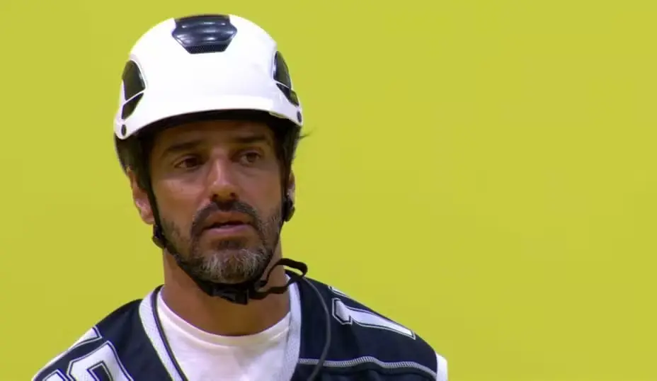 Alberto Cowboy é um homem de meia idade de barba grisalha e cabelo preto. Na foto, ele está com equipamento de proteção durante a Prova do Líder.