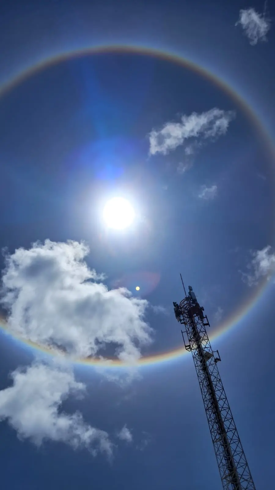 Halo solar no céu de Fortaleza, anel multicolorido ao redor do sol.