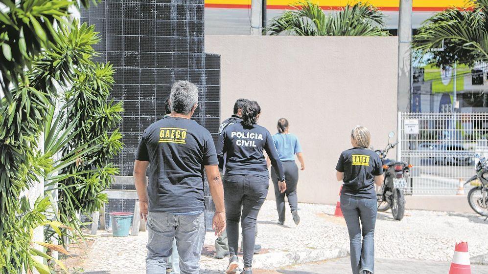 pessoas de costas com blusas da policia civil e gaeco, ceará, durante operacao, buscas por criminosos faccionados.