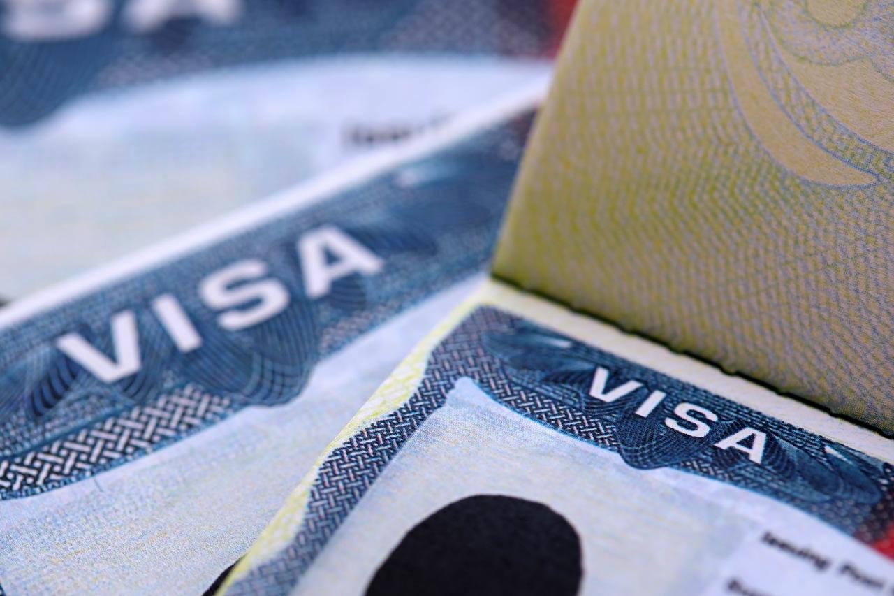 Close-up de páginas de passaporte com visto americano estampado, simbolizando processos de imigração e solicitação de visto para os Estados Unidos.