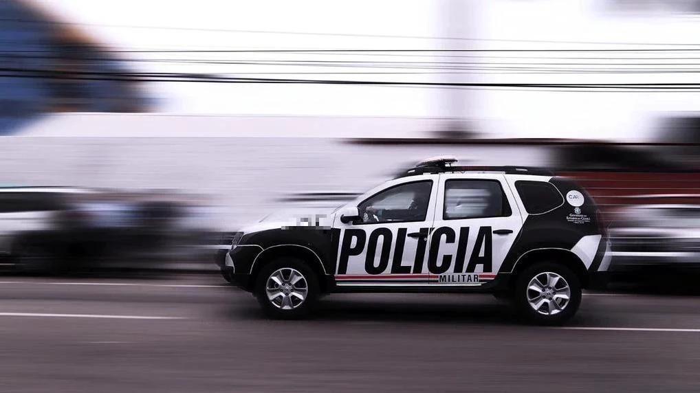 A imagem mostra uma viatura da Polícia Militar do Ceará, nas cores preto e branco, em alta velocidade em uma via.