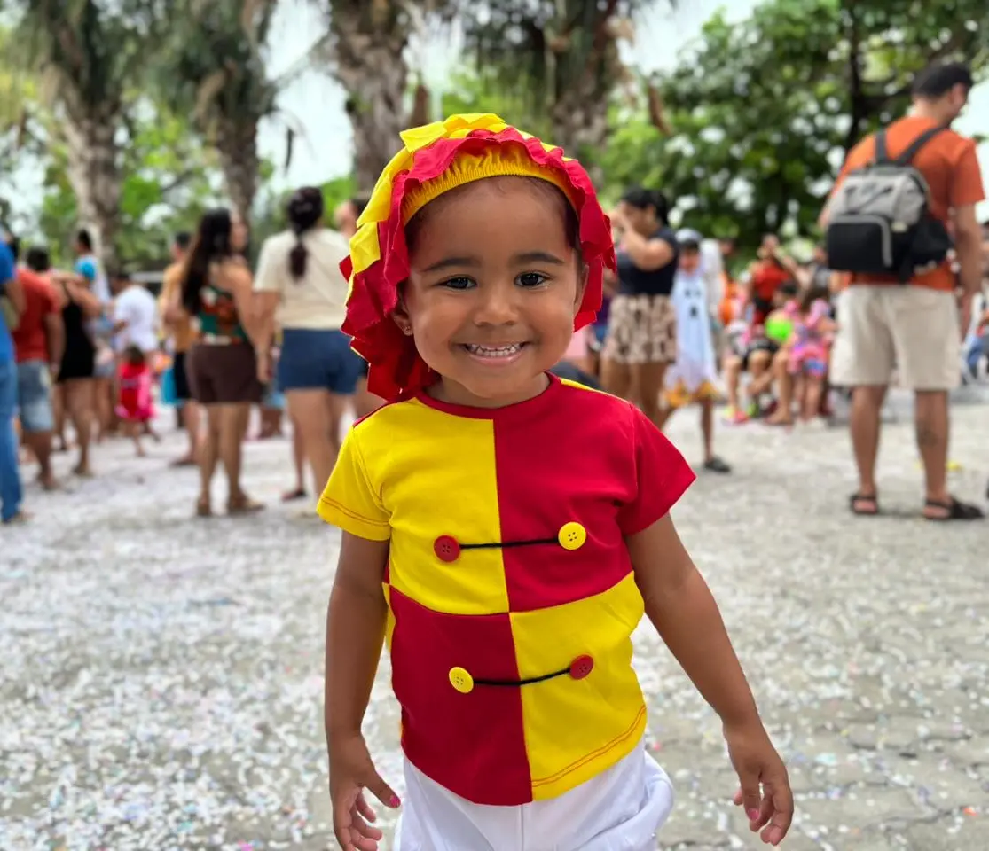 Criança vestida de Emilia sorri para a câmera.