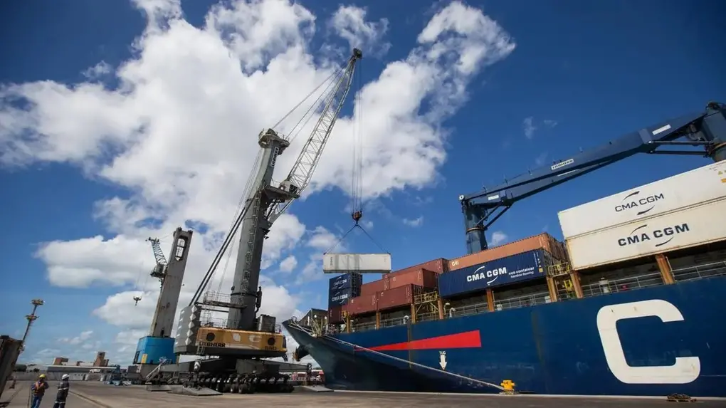 Corte de contêineres em porto, com guindaste movimentando carga para navio de carga, logística e transporte marítimo.