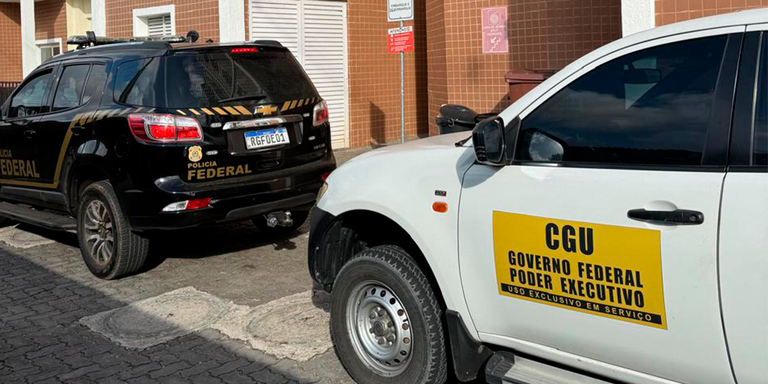 Viaturas da Polícia Federal e da CGU estacionadas lado a lado em frente a um prédio; o carro branco exibe adesivo ‘CGU Governo Federal Poder Executivo’ e o preto identifica a Polícia Federal.