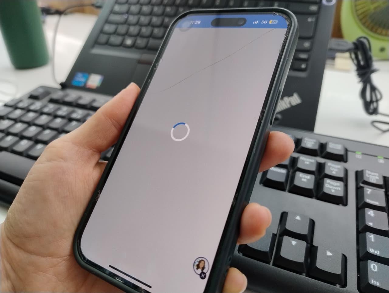 Mão segura o celular com o aplicativo do Meu INSS instável.