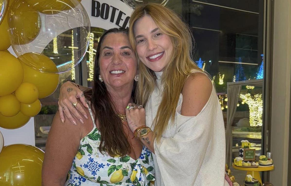 Margareth Serrão ao lado de Virginia. As duas vestem roupas claras e estão sorrindo, posando na frente de balões amarelos.