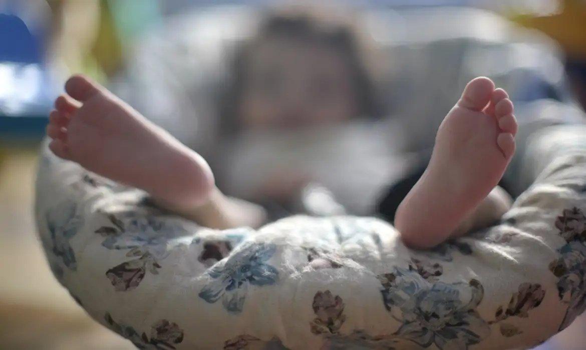 Dois pés de bebê recém-nascido em cima de almofada.