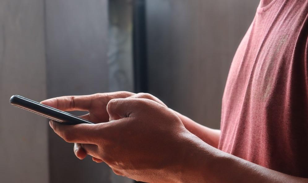 Homem não identificado segura celular.