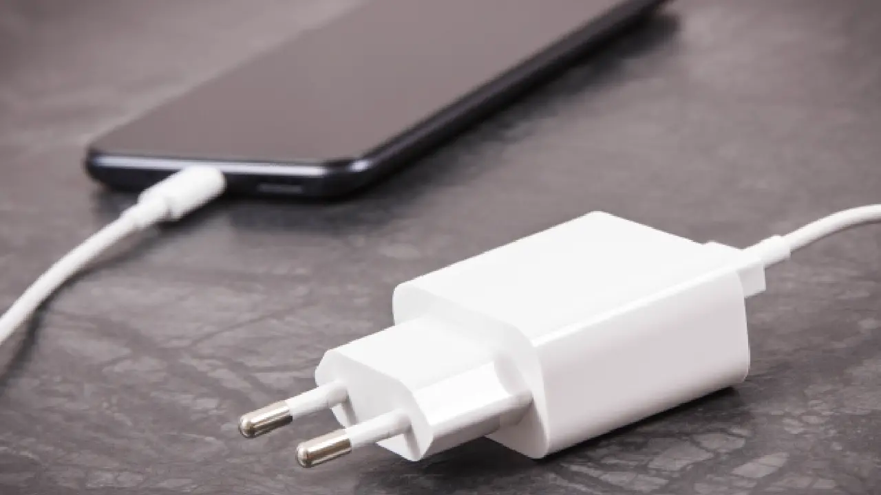 Carregador de celular ligado ao aparelho em cima de uma mesa