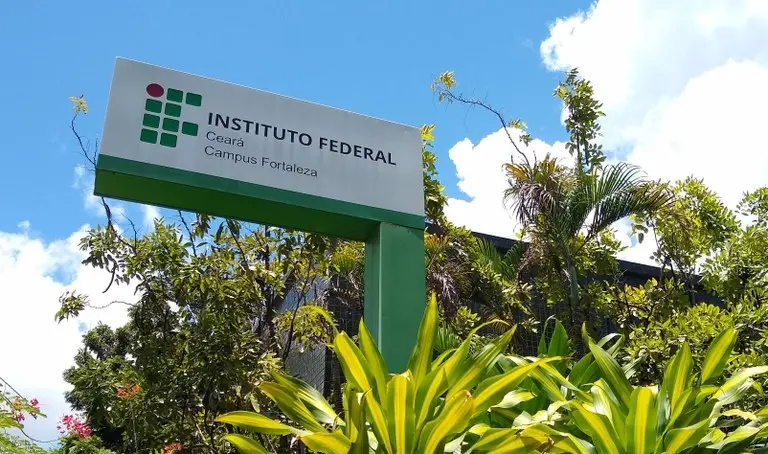 Imagem do sinal do Instituto Federal Ceará Campus Fortaleza, visível ao ar livre com vegetação ao redor e céu claro ao fundo.