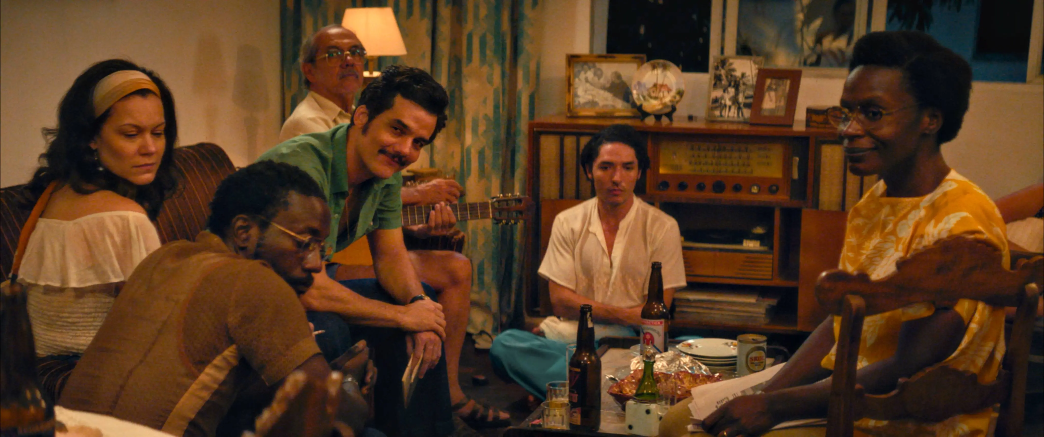 Cena de um jantar com várias pessoas sorrindo e conversando em um ambiente aconchegante, celebrando momentos especiais com amigos, com bebidas e comida na mesa.