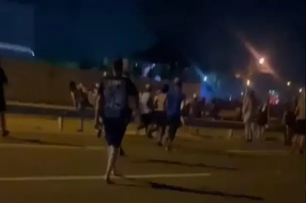 A imagem mostra uma correria entre torcedores, em uma estrada, à noite, em Fortaleza.