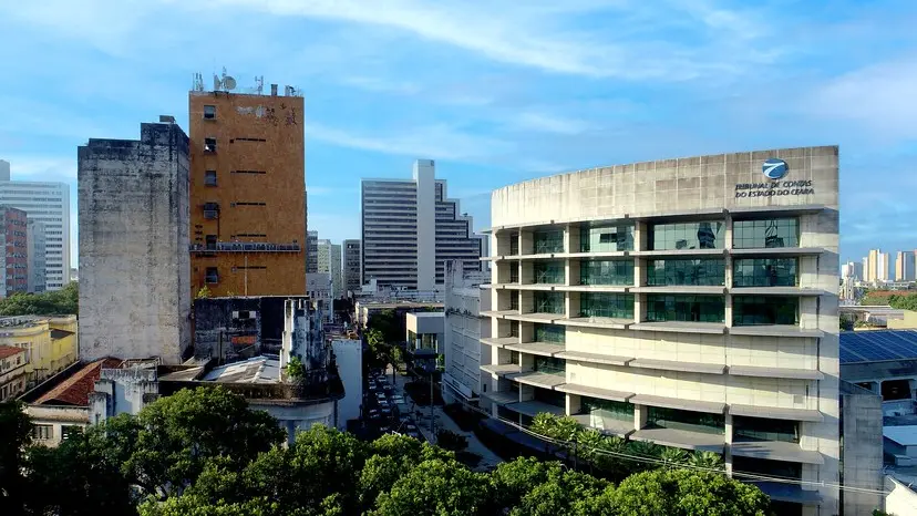 Vista urbana com prédios no centro de Fortaleza; à direita, o edifício moderno do Tribunal de Contas do Estado do Ceará, sob céu azul com poucas nuvens.