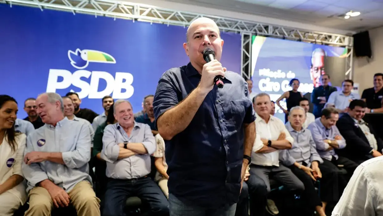 Roberto Cláudio durante evento do PSDB. De pé, ele discursa para apoiadores. Atrás dele, sentados, estão outras lideranças políticas, como Ciro Gomes, Tasso Jereissati e José Sarto.