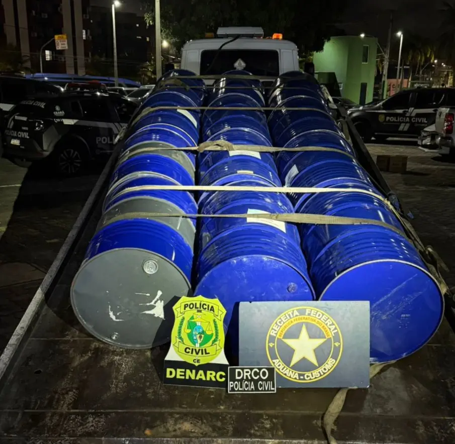 A imagem mostra vários tonéis azuis apreendidos em uma operação da Receita Federal e da Polícia Civil, em cima de um caminhão-reboque.