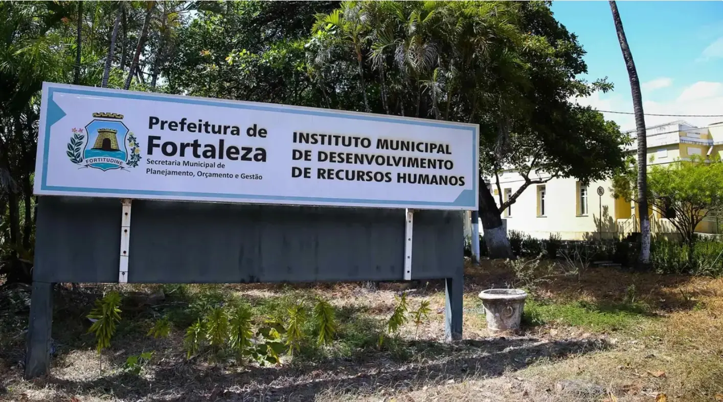 Uma placa branca horizontal e retangular, com bordas azuis, identifica a 