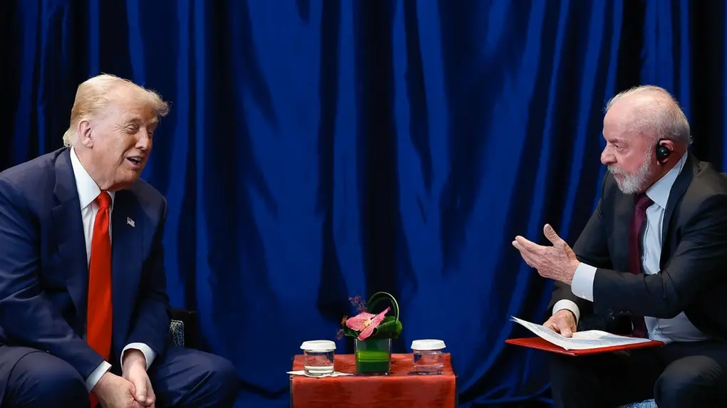 Lula e Trump conversam pessoalmente em frente a uma cortina azul.