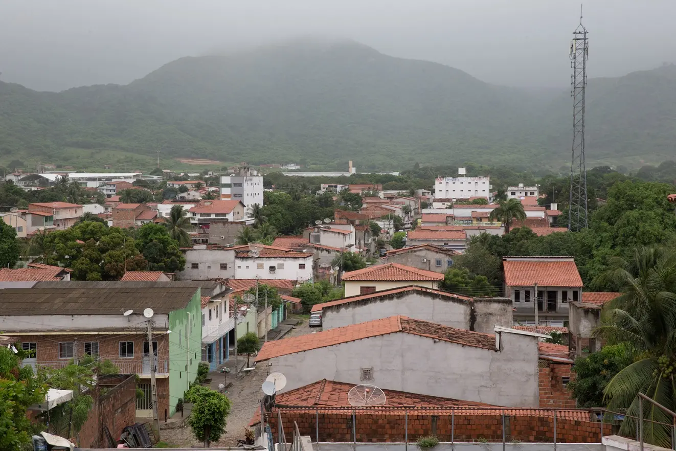 Vista aérea de Itapipoca, no Ceará, com colina com névoa ao fundo e, abaixo, casas simples.