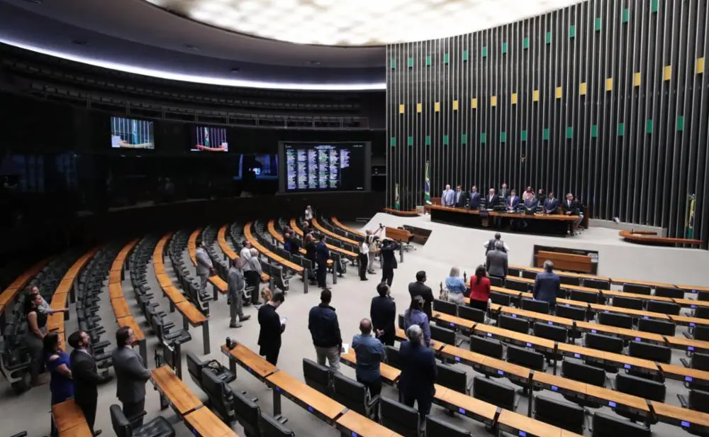 Plenário da Câmara dos Deputados. Parlamentares estão sentados nas poltronas da Casa e na Mesa Diretora.