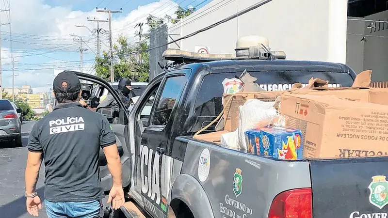 A foto mostra policiais civis em atuação, próximo de uma caminhonete da Polícia Civil, com vasto material apreendido, em caixas.