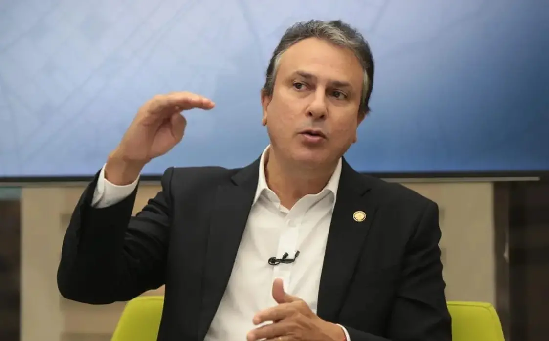 Camilo Santana gesticula enquanto concede entrevista para a TV Verdes Mares. Na foto, ele usa terno preto e camisa social branca.