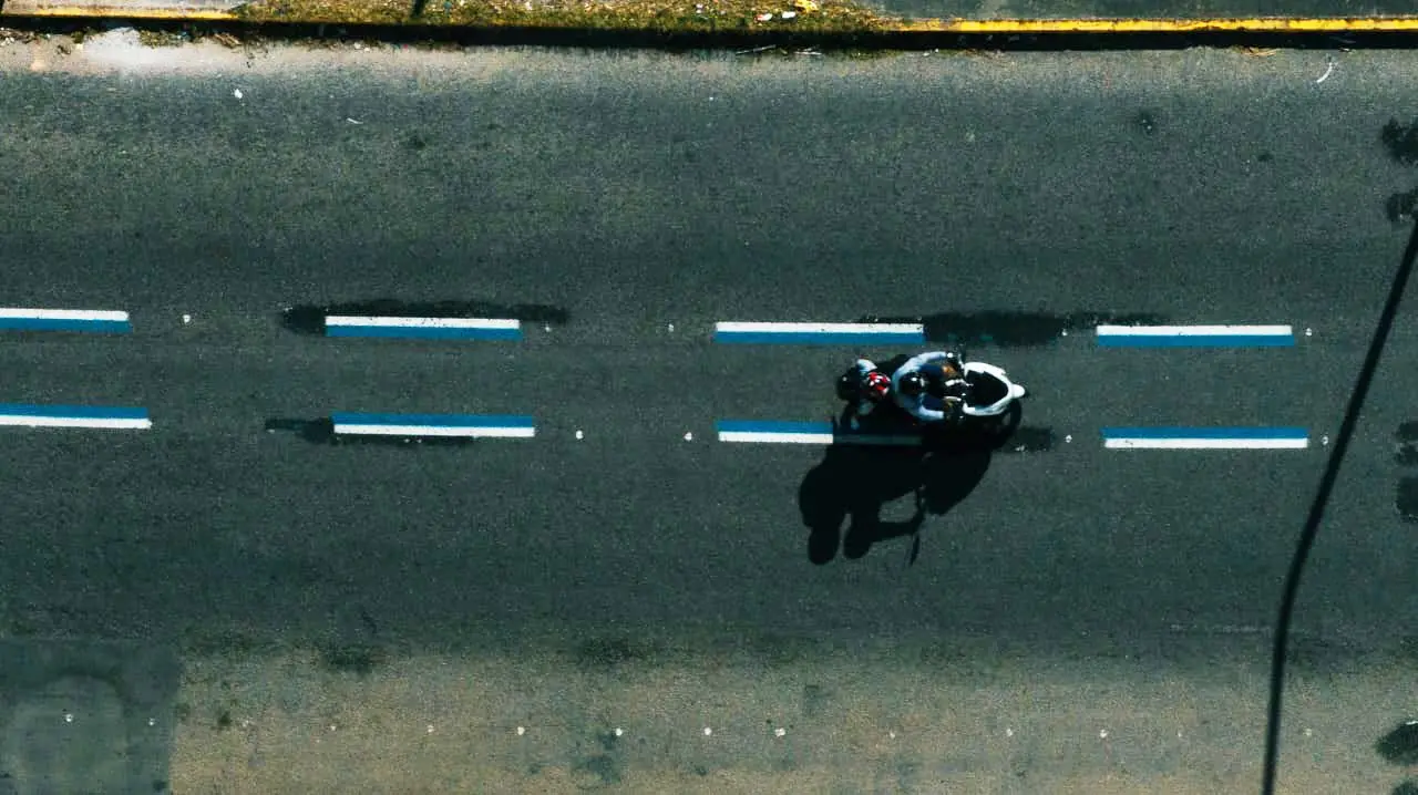 Imagem aérea mostra motociclista trafegando em faixa preferencial pintada de azul em avenida de Fortaleza.