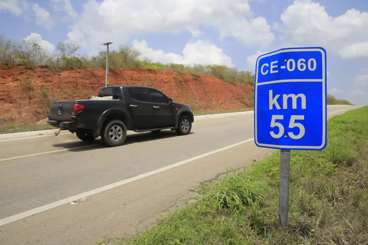 Trecho da rodovia CE-060, com placa do km 55 e veículo passando na estrada.