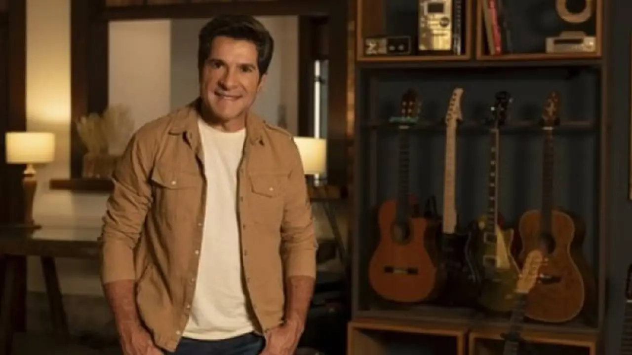 O cantor Daniel esta posando para foto no estúdio do programa com a mão no bolso e sorrindo.