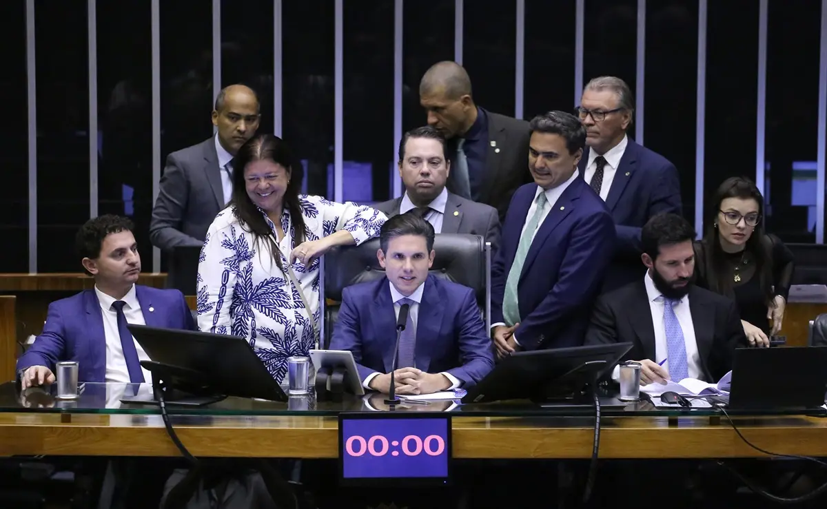 Presidente da Câmara, Hugo Motta, rodeado de parlamentares, na Mesa Diretora da Câmara dos Deputados.