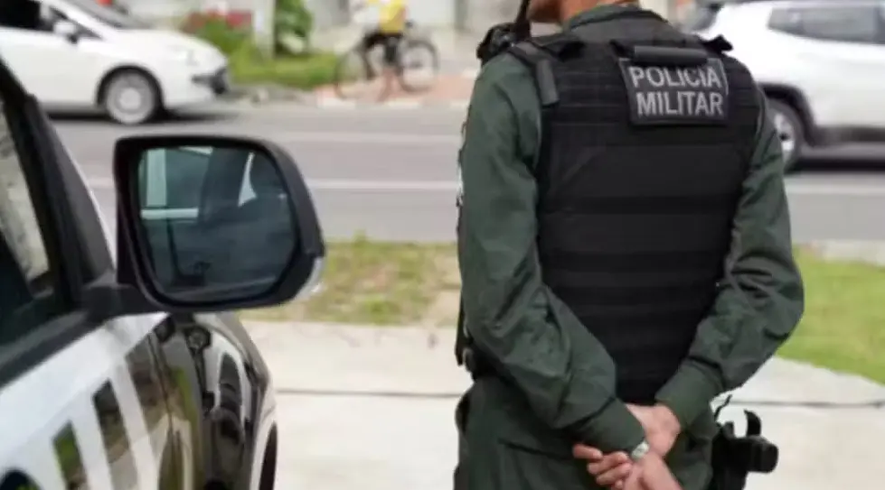 policial militar fardado de costas ao lado de viatura.