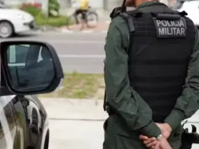policial militar fardado de costas ao lado de viatura.