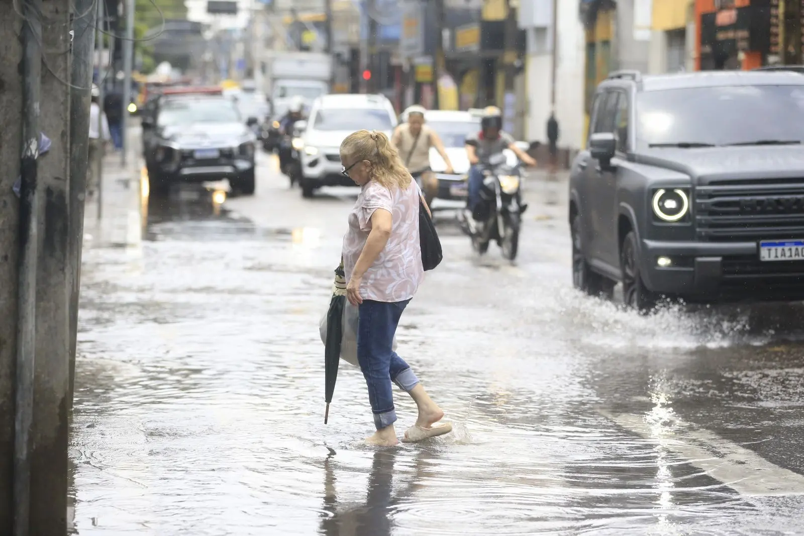 Mulher caminha em rua alagada de Fortaleza.