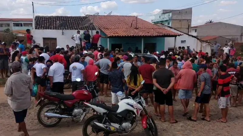 chacina pessoas olhando local moto aglomerado de gente em frente a uma casa.