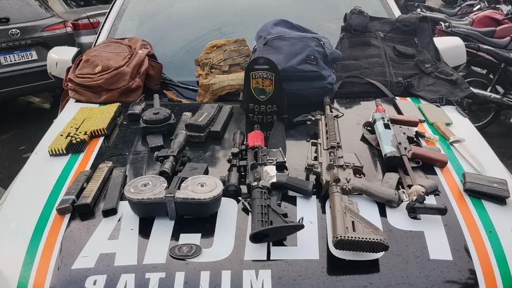 Armamento apreendido pela polícia em operação que inclui pistolas, escopeta, munições e equipamentos táticos, exibidos sobre o veículo policial com a logomarca da Polícia Militar no Ceará.
