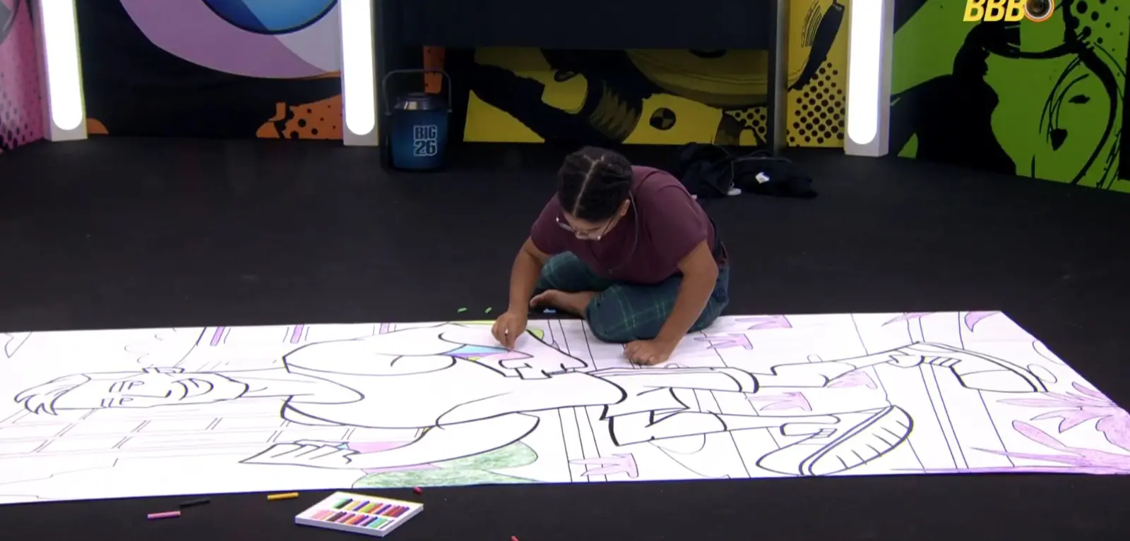 Foto da participante Milena do BBB 26 colorindo uma imagem do participante Jonas durante o desafio Barrados do Baile.