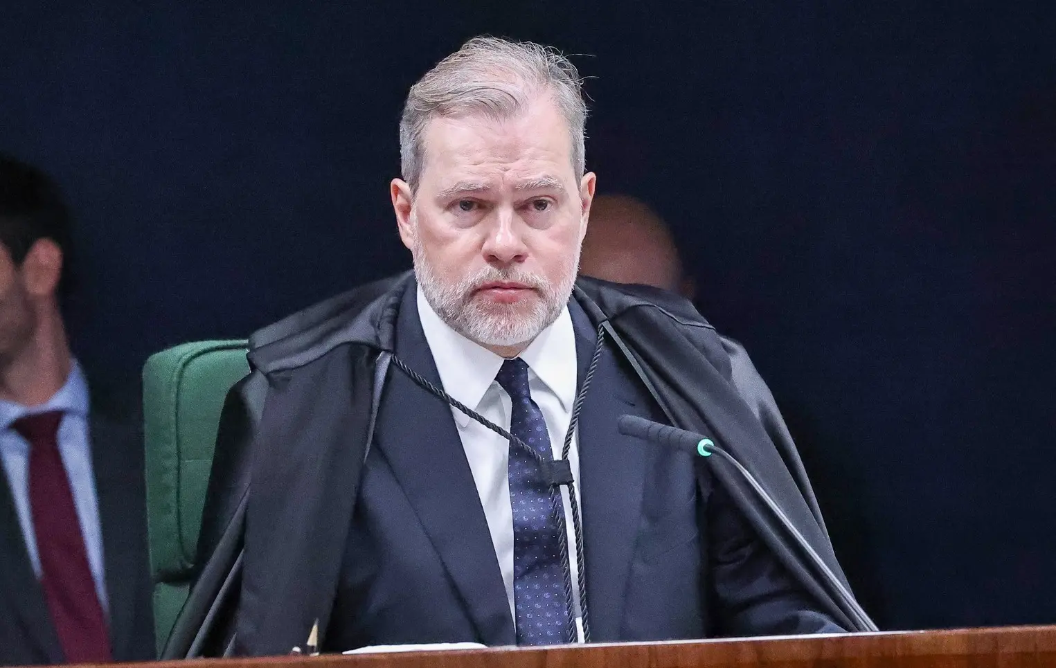 Dias Toffoli é um homem branco de cabelo liso ralo grisalho e barba bem cortada da mesma cor. Na foto, ele está com semblante sério e veste terno preto com camisa social branca e gravata azul.