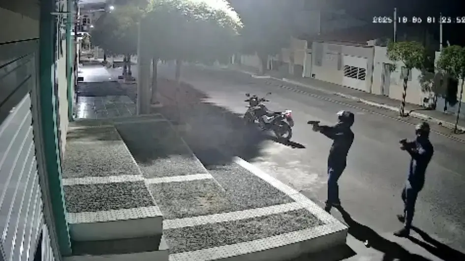 Foto de câmera de segurança noturna mostrando dois policiais armados com pistolas, um deles com capacete, em uma rua escura com uma motocicleta estacionada ao fundo. Imagem usada em matéria sobre atentado contra vereadora do Rio Grande do Norte.
