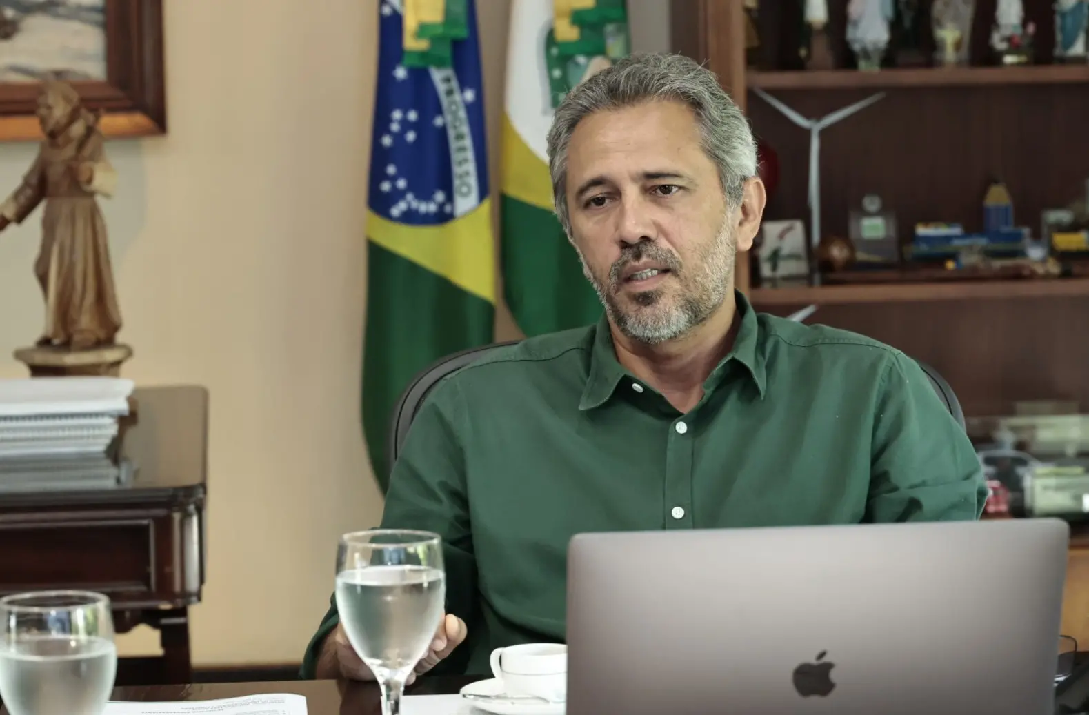 Elmano de Freitas é um homem de meia idade, de cabelo e barba grisalhos. Na foto, ele está de frente para um notebook e usa camisa social verde.