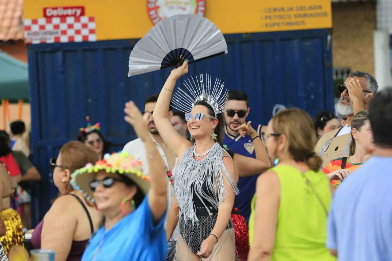 Foliã segura leque prateado. Ela está vestida com uma fantasia da mesma cor.