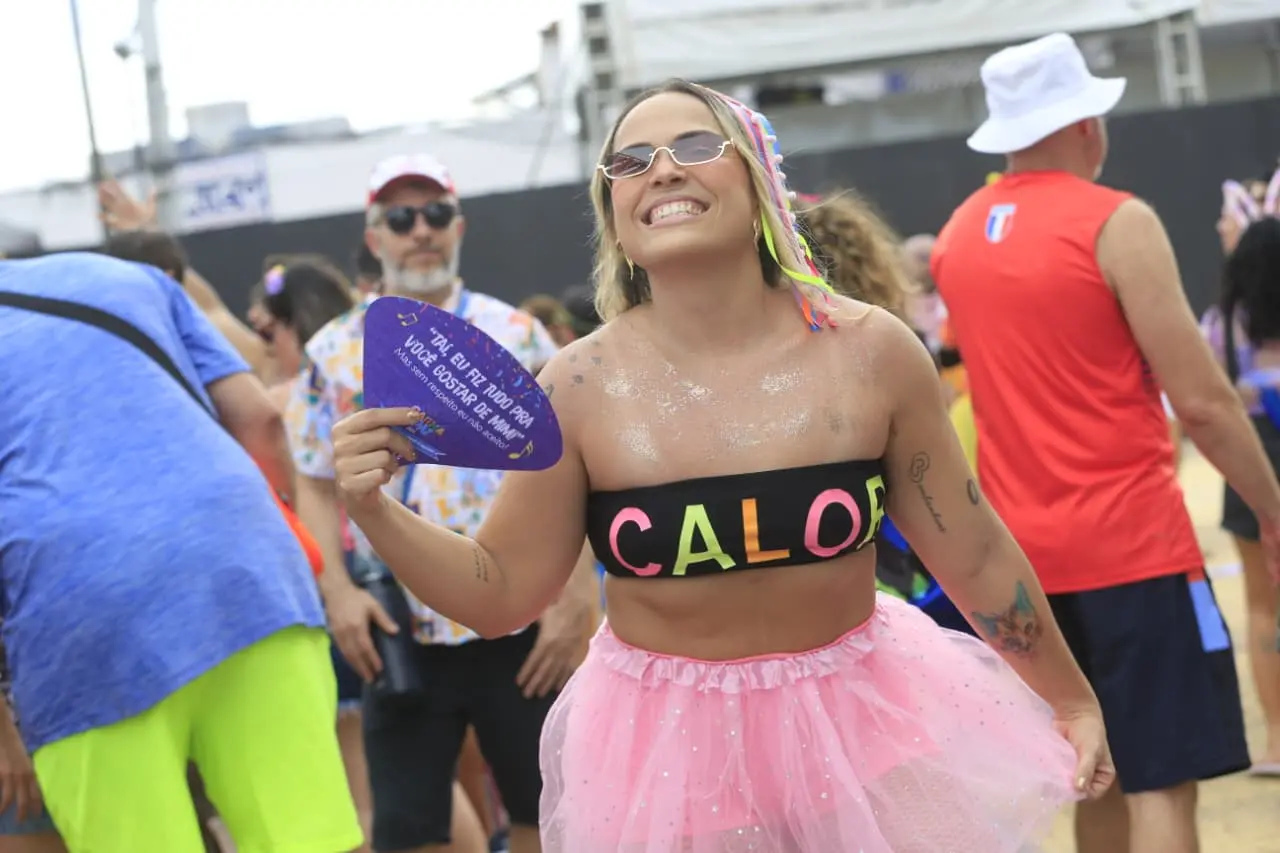 Foliã com top escrito CALOR. Ela usa uma saia rosa de tule.