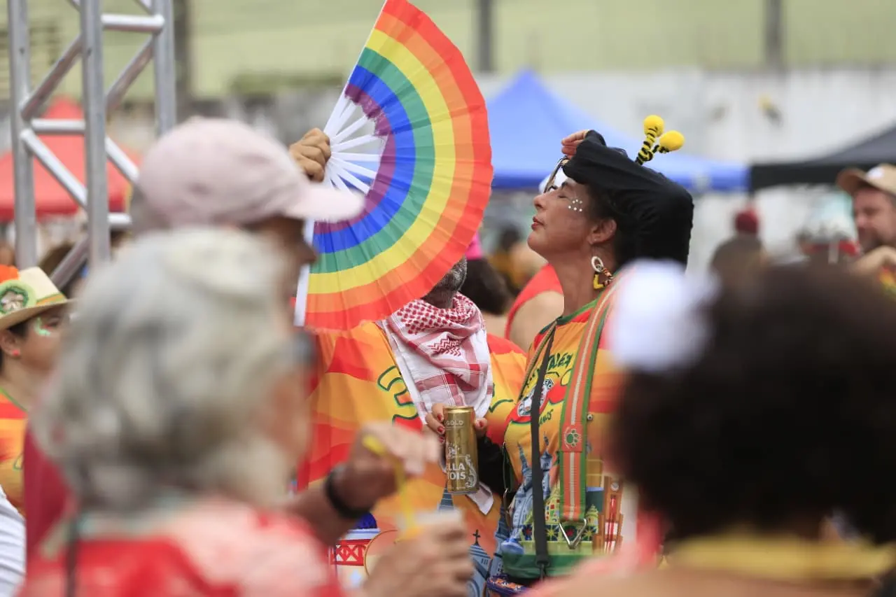 Foliã recebe vento de leque no rosto. O leque é com as cores do arco íris.
