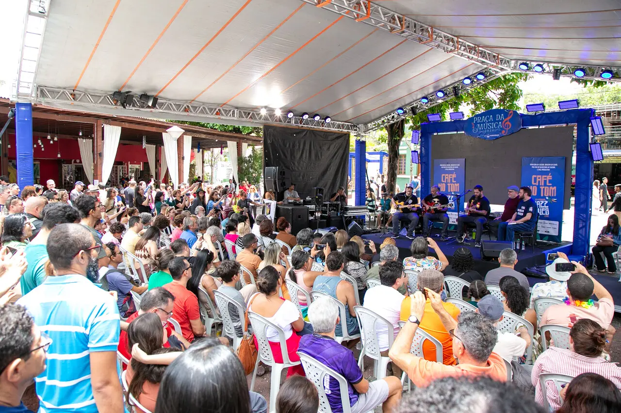 Imagem parcial de público sentado em praça assistindo músicos de jazz em um palco, em praça de Guaramiranga.
