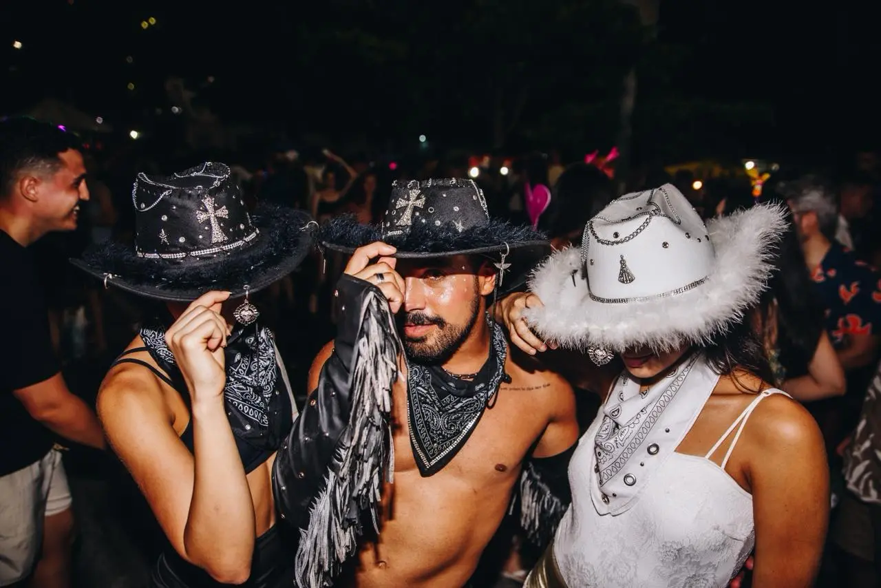Trio de amigos mostram chapéus de cowboy preto e branco em Carnaval de Fortaleza.