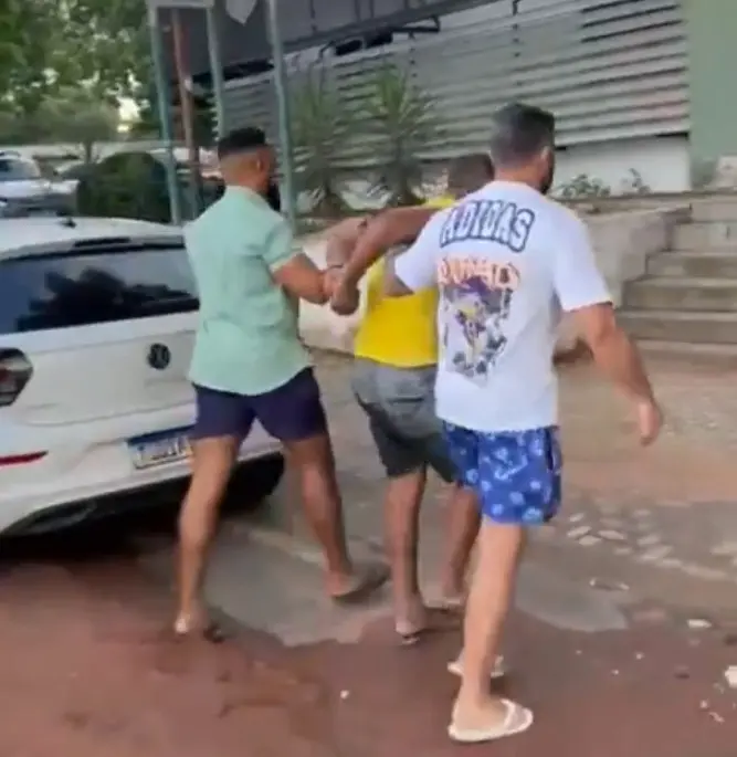 homem preso conduzido por dois policiais à paisana.