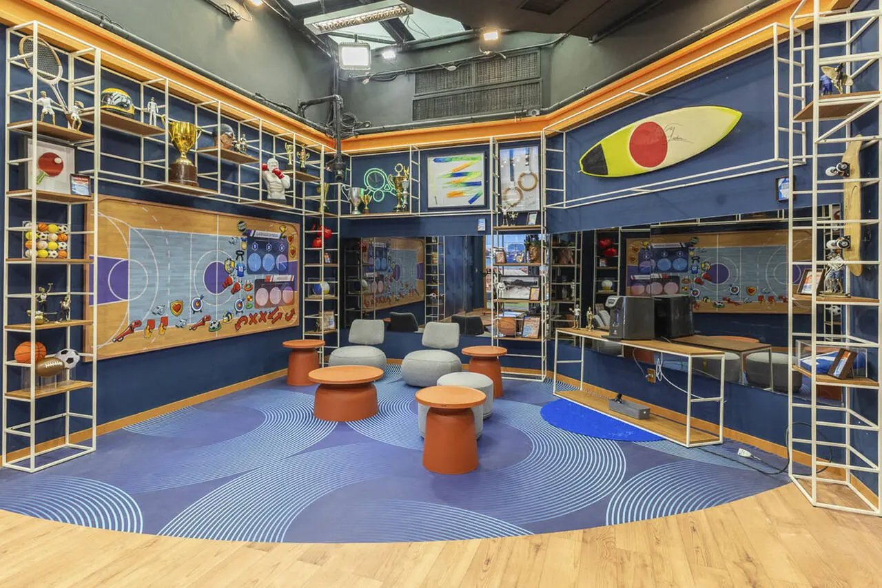 Quarto multicolorido com pufes cinzas e várias prateleiras.