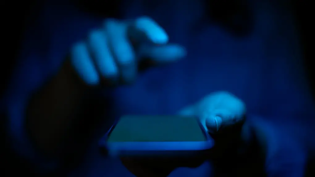 celular homem segurando misterio luz azul.