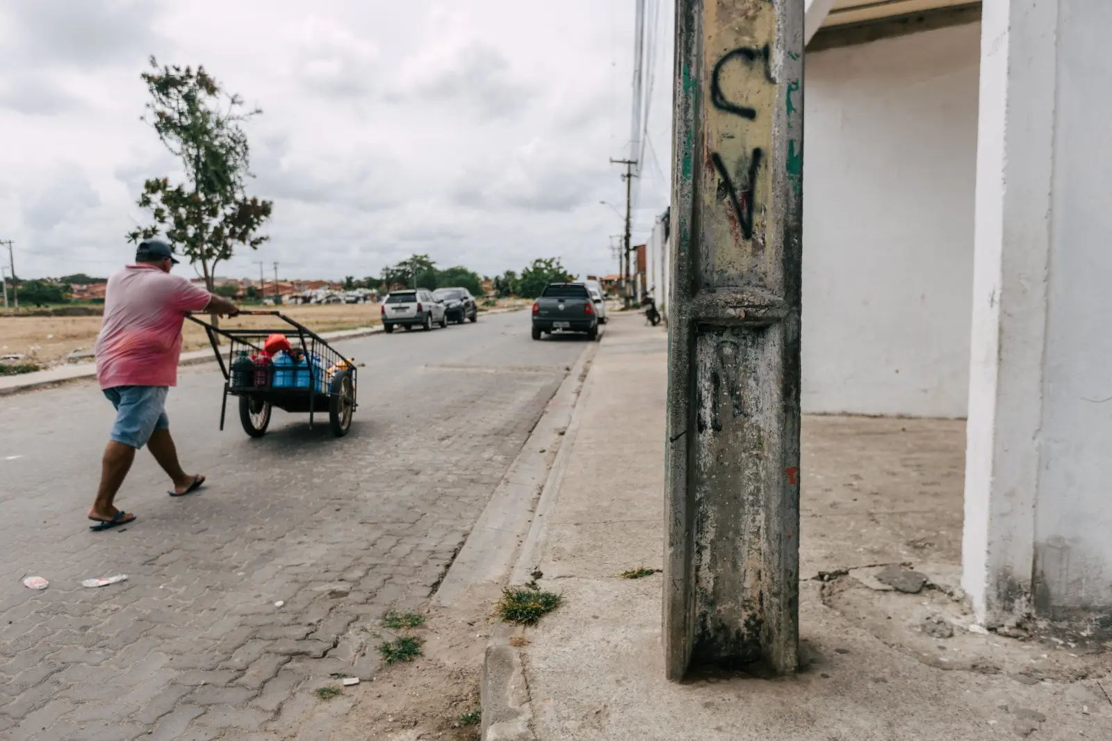 poste pichado cv sigla faccao homem empurrando carrinho via publica.