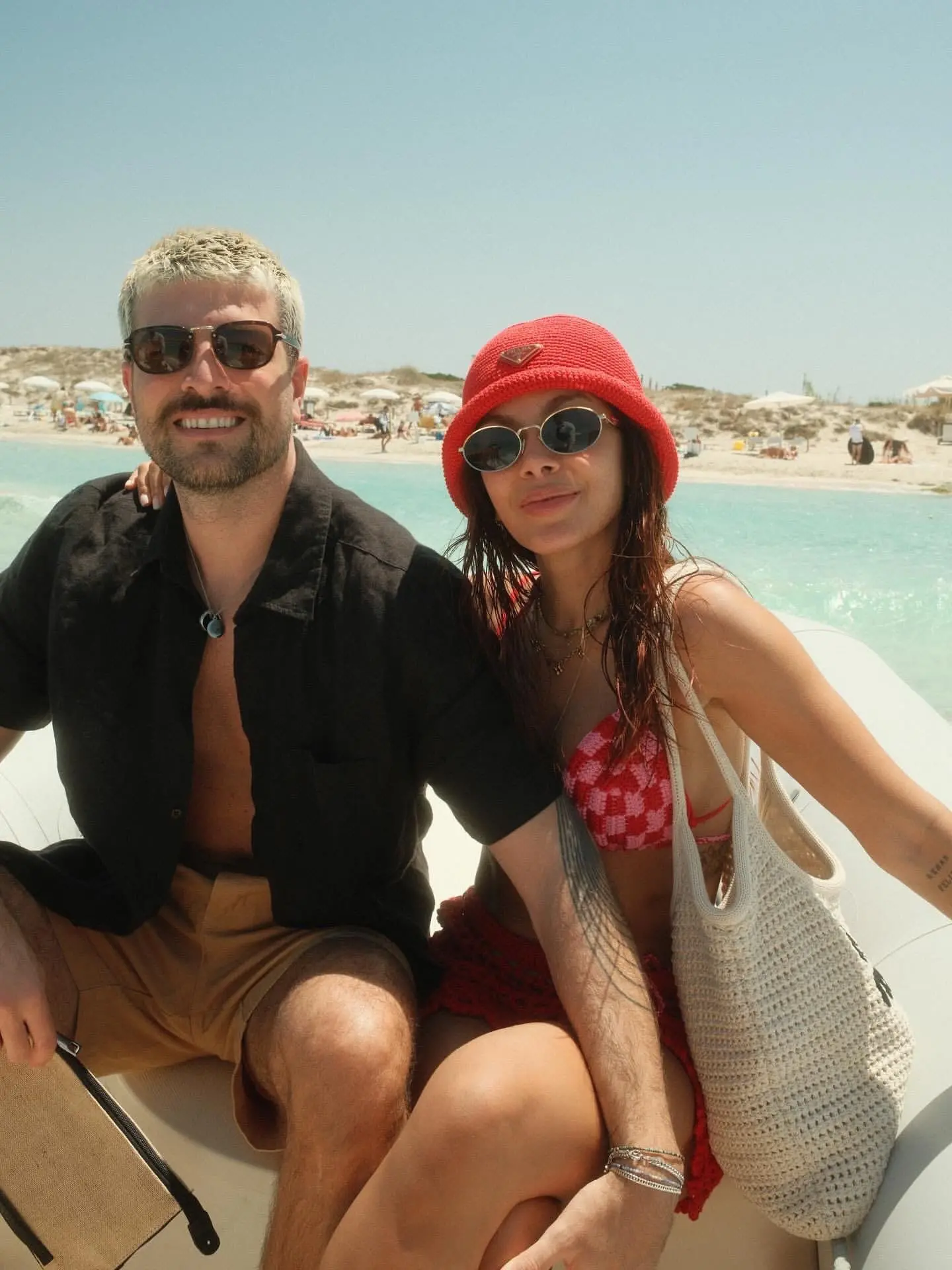 Anitta posa com a mão no ombro de ex-namorado, em barco, com mar ao fundo.